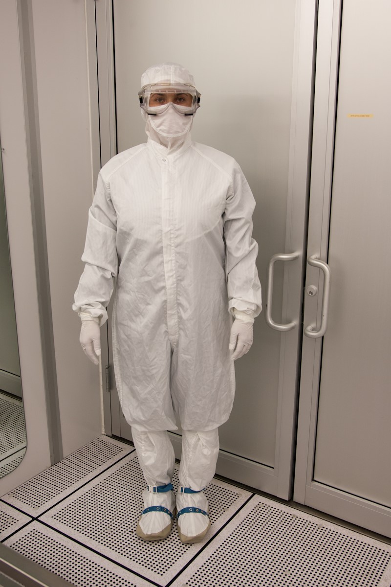 Lab researcher wearing cleanroom attire: sterile and non-sterile hood, coverall, frock, boots, facemask and sleeve cover with non-linting yarns, high-density construction and anti-static carbon fibers.